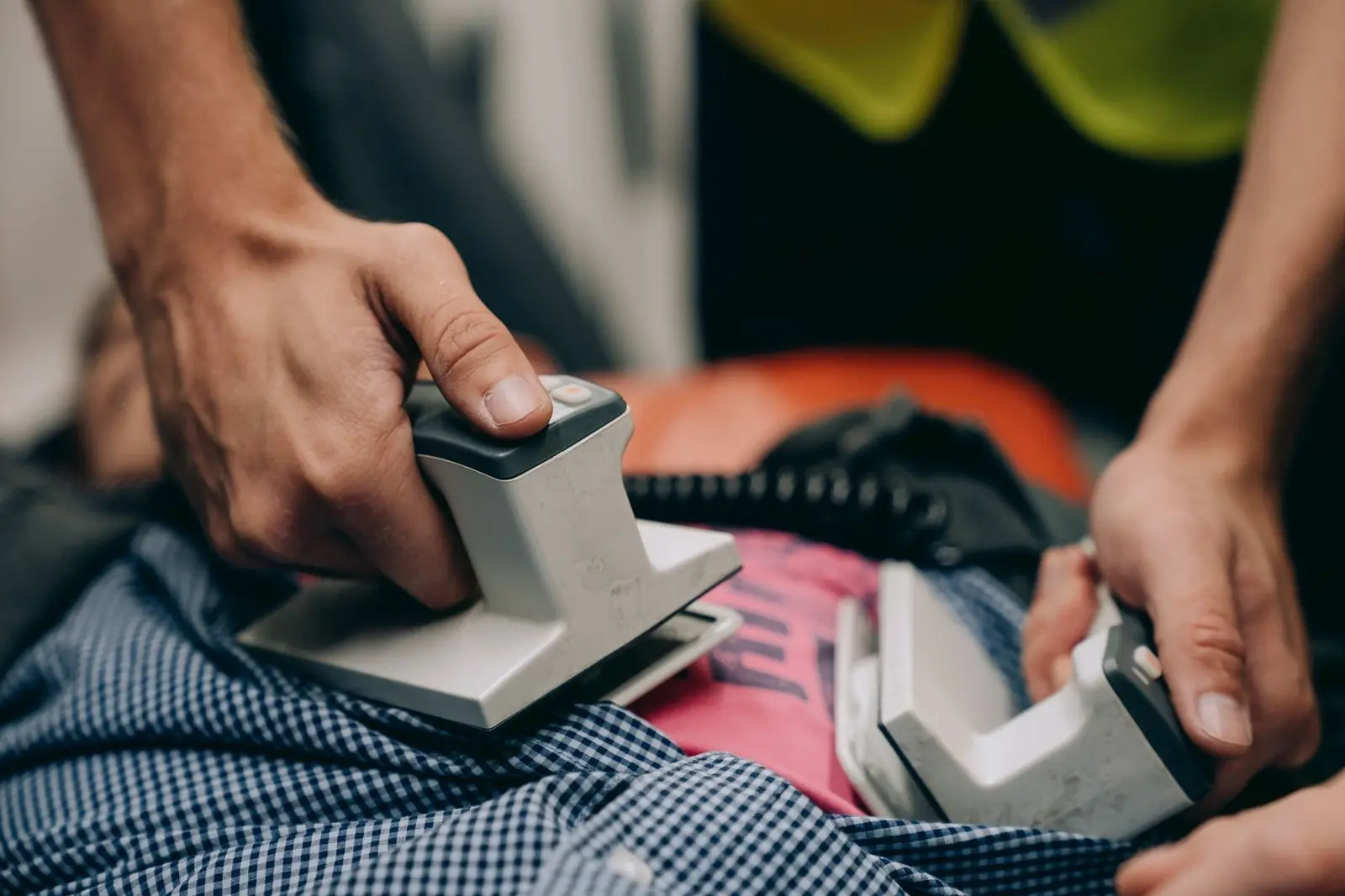 Paramedic's hands holding defibrillator paddles