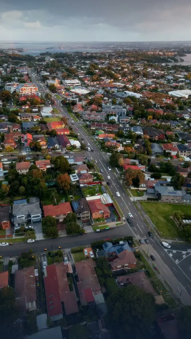 Aerial view of a suburb at dusk, with a main road running through it