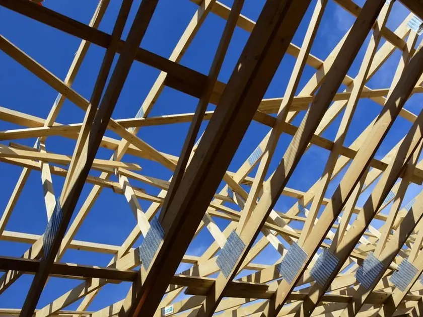 Timber roof trusses on a new home under construction against a deep blue sky