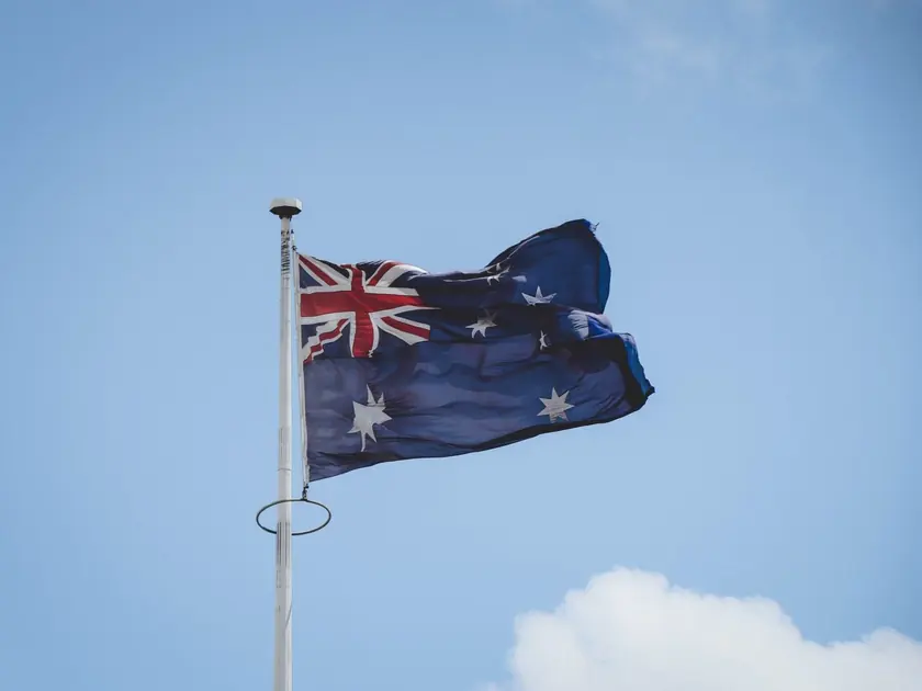 The Australian flag flying against a clear blue sky.
