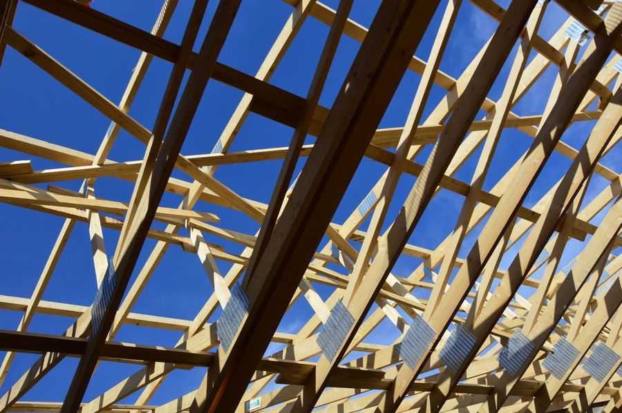 Timber roof trusses of a new home under construction against a deep blue sky
