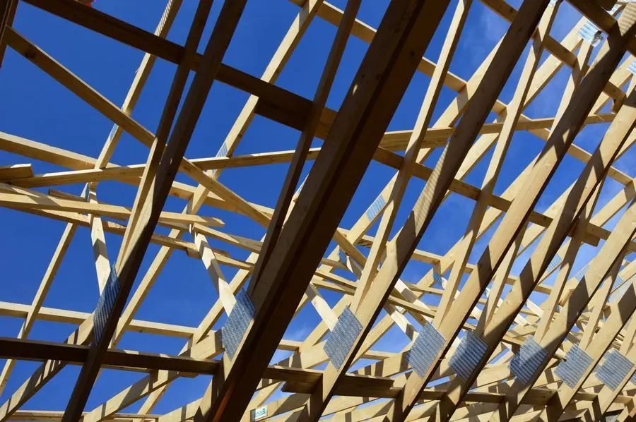 Timber roof trusses of a new home under construction against a deep blue sky